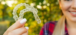 teenage girl holding clear aligners outside