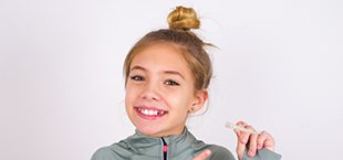 teen girl holding and pointing to a clear aligner