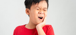 Child holding his face with dental pain