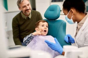 little boy pointing to tooth pain in the dentist chair