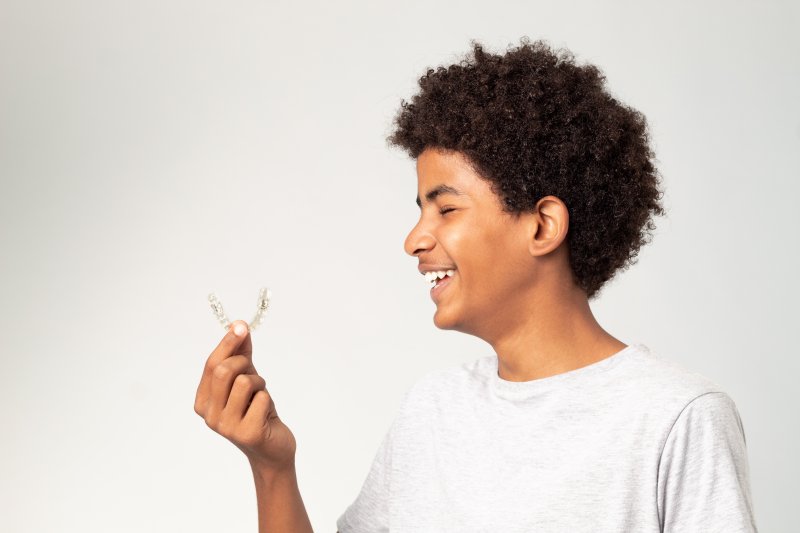 teen boy smiling and looking at his clear aligner