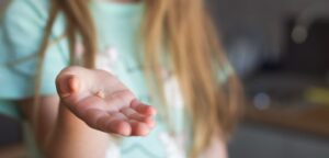 little girl’s hand holding a baby tooth